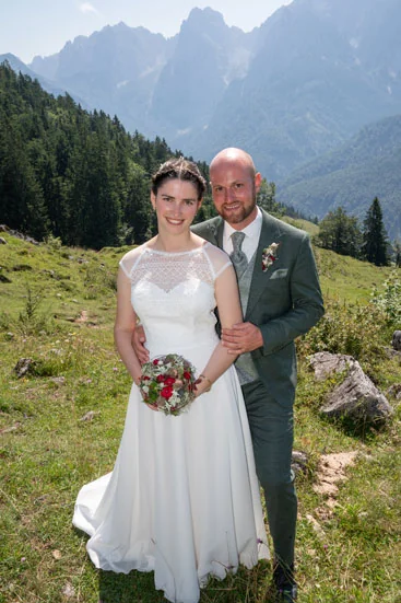 Braut und Bräutigam stehen nach der Hochzeit gemeinsam in alpiner Berglandschaft