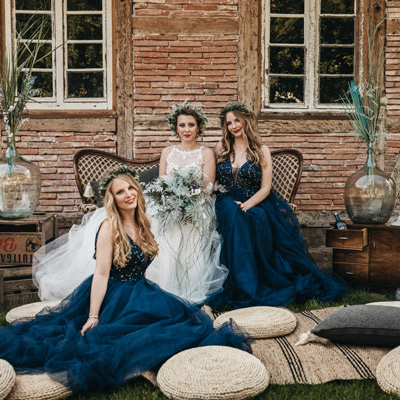 Die Braut im weißen Kleid mit den zwei Brautjungfern in dunkelblauen Abendkleid